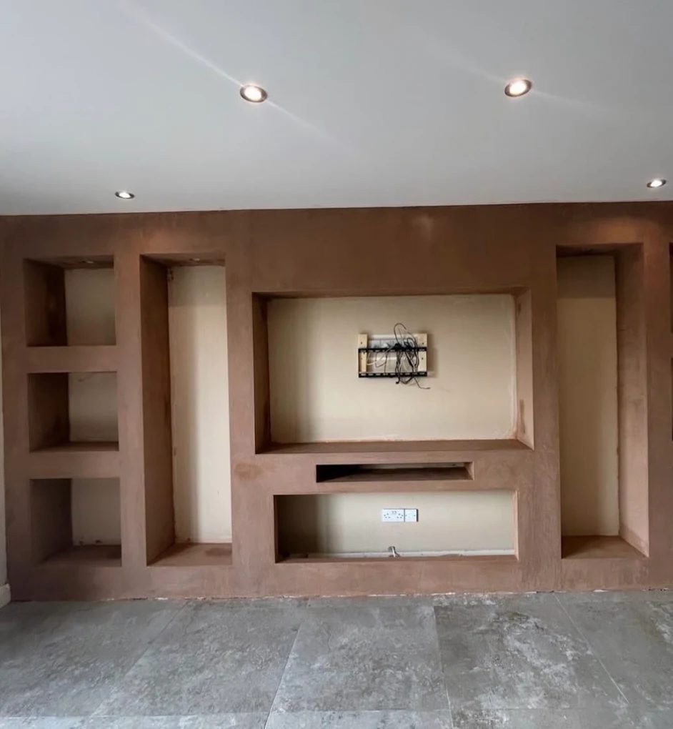 Plastered media wall with recessed shelving and a TV opening